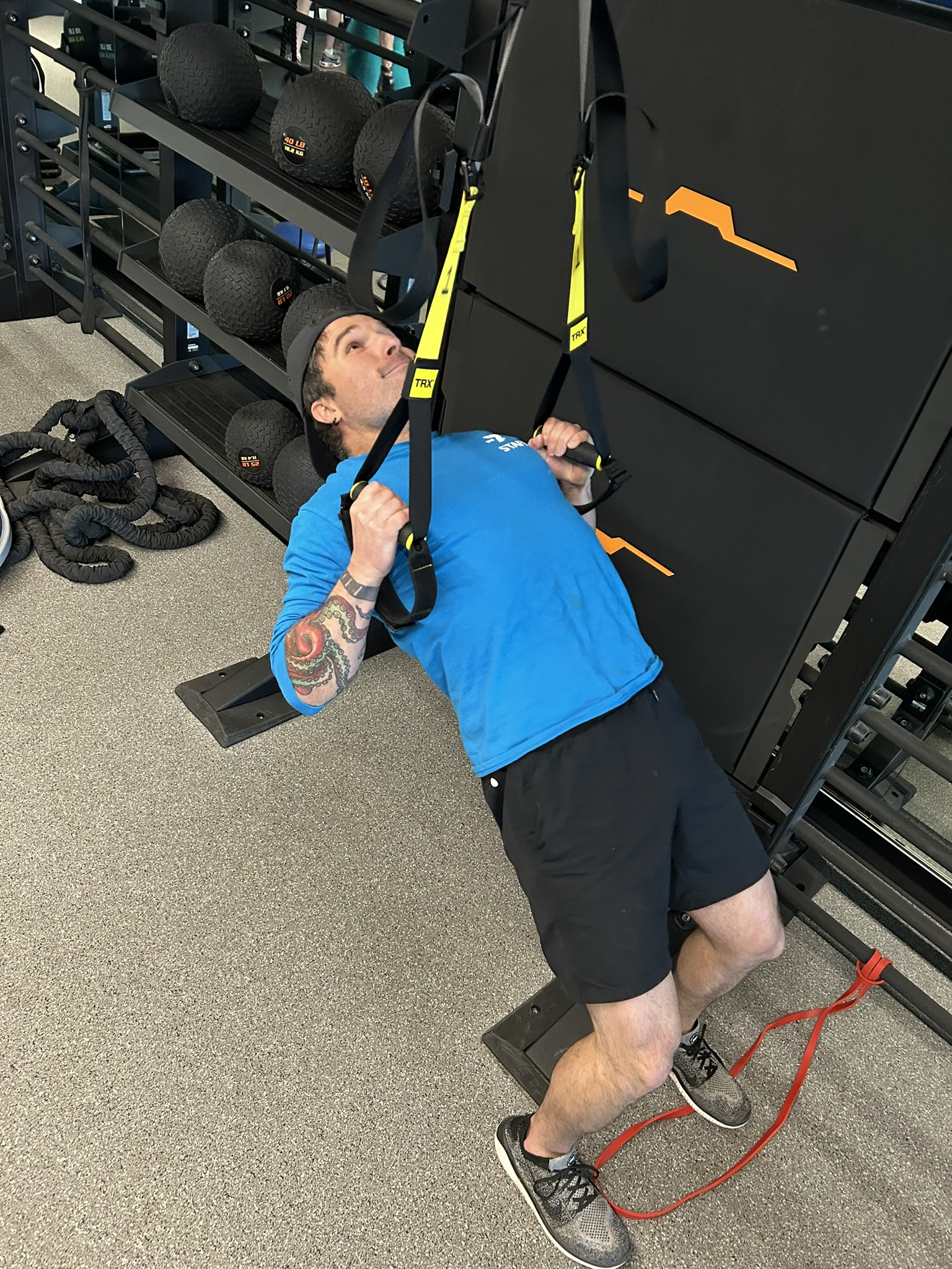 Y trainer demonstrates a TRX row exercise in the Wellness Center