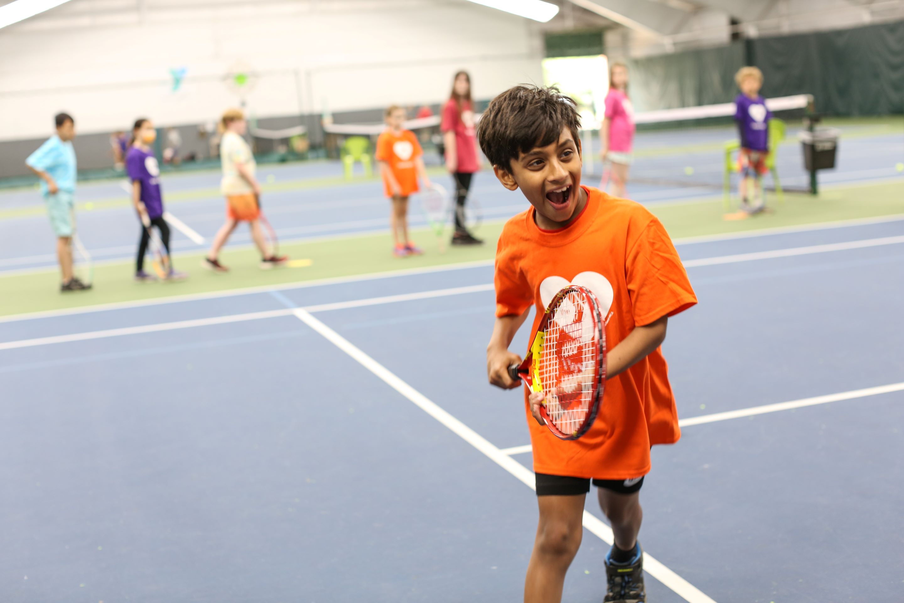 Youth playing tennis at the Eugene Family YMCA tennis camp