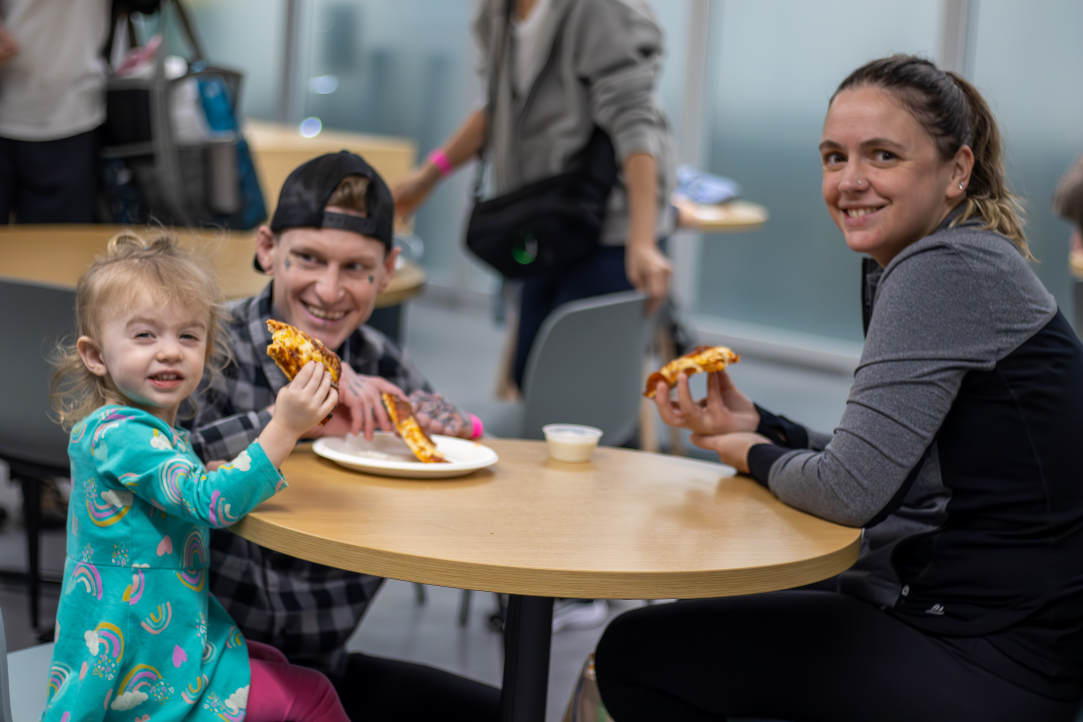 three Y members smiling while participating in Pizza Pickleball Pool Family Fun Night.