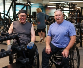 two men in wheelchairs use free weights and ADA equipment in ymca gym