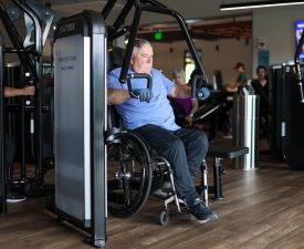 man in wheelchair lifts weights in the YMCA gym